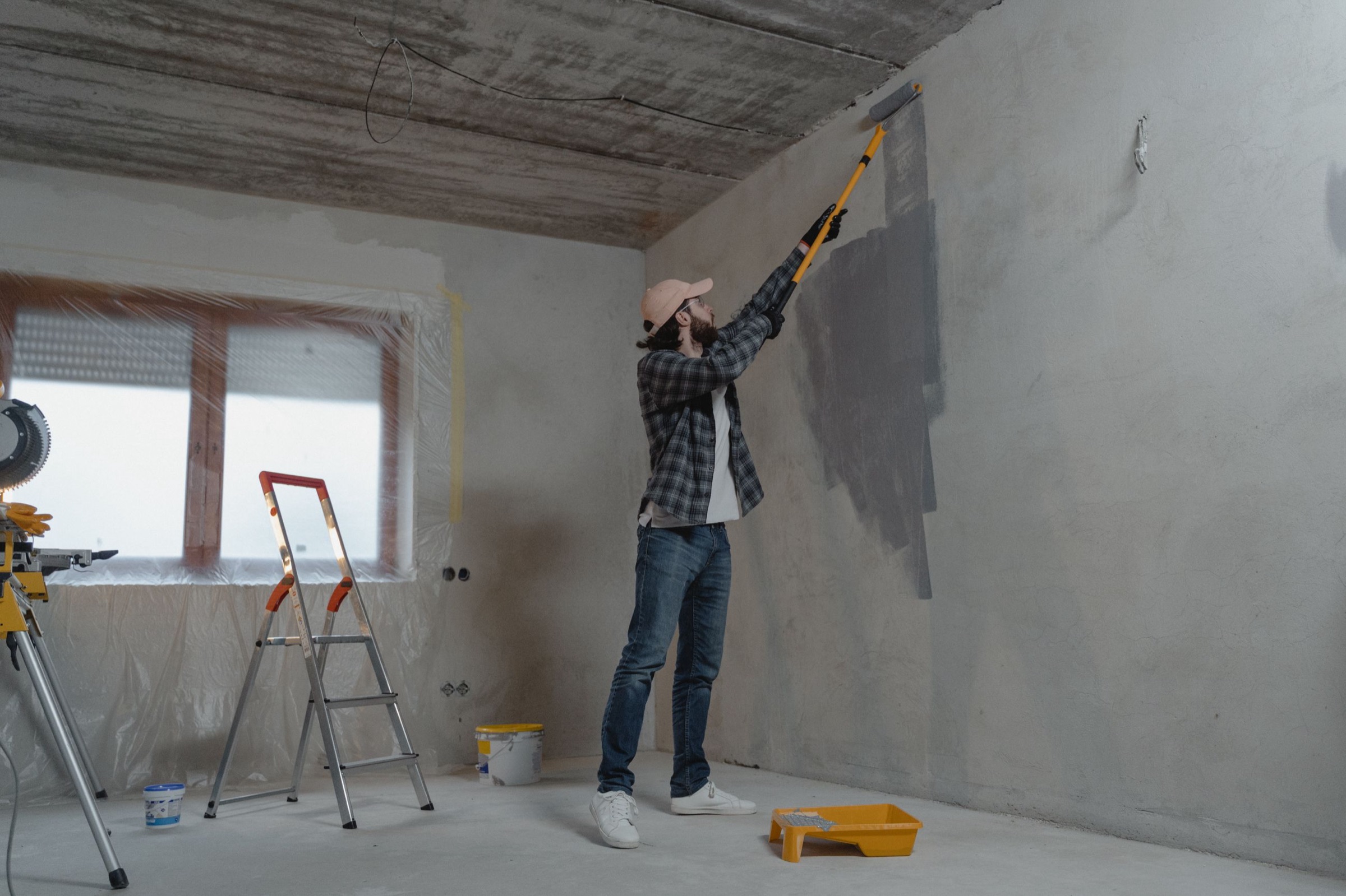 A professional painter rolling a fresh coat onto an interior wall